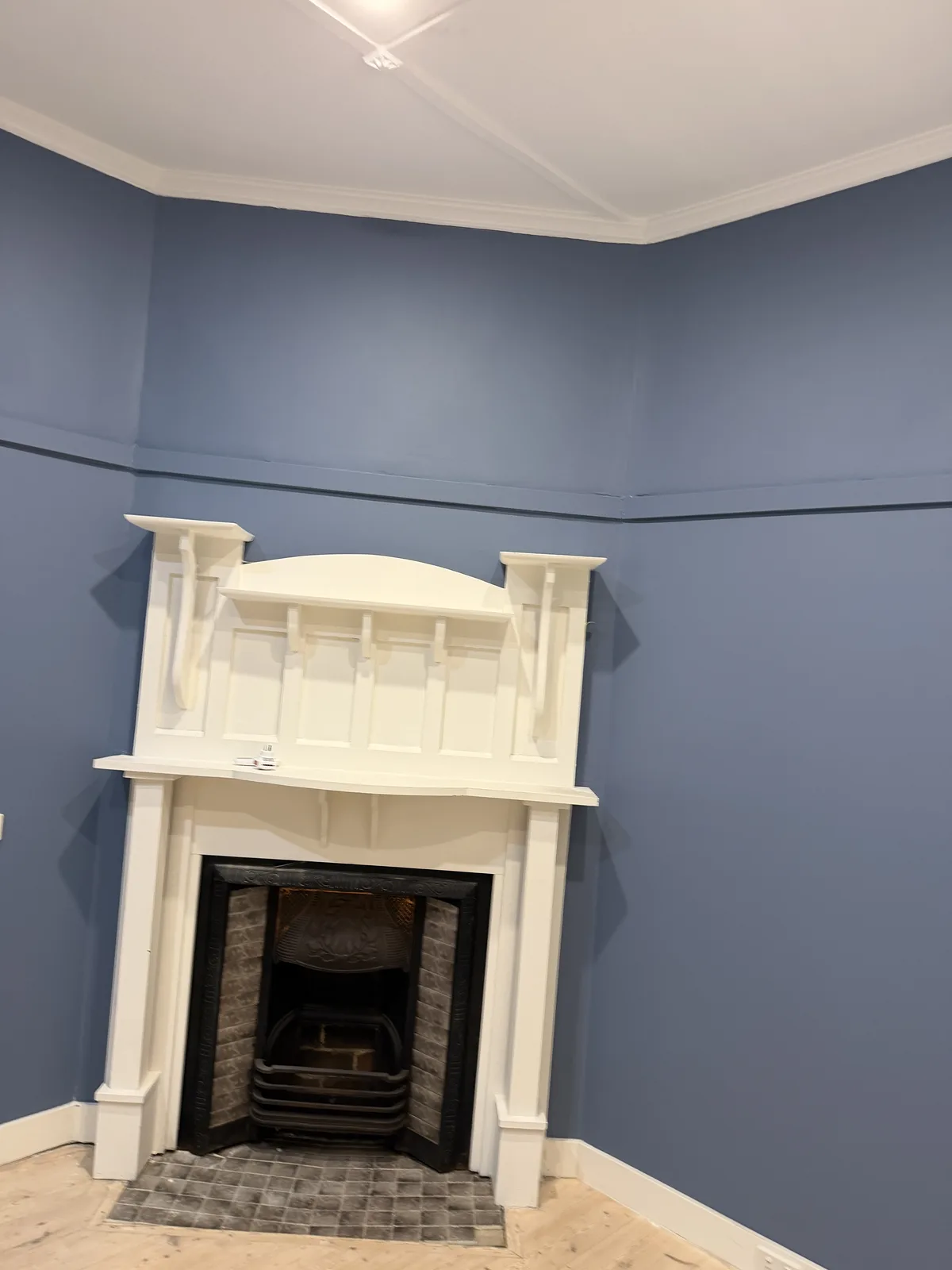 Blue interior wall and white fireplace after crack repairs and repainting